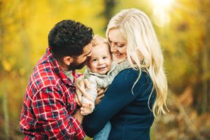 A young family are all smiles as they shower their one year old son with hugs and kisses during their fall family photo session atop Mt. Lemmon