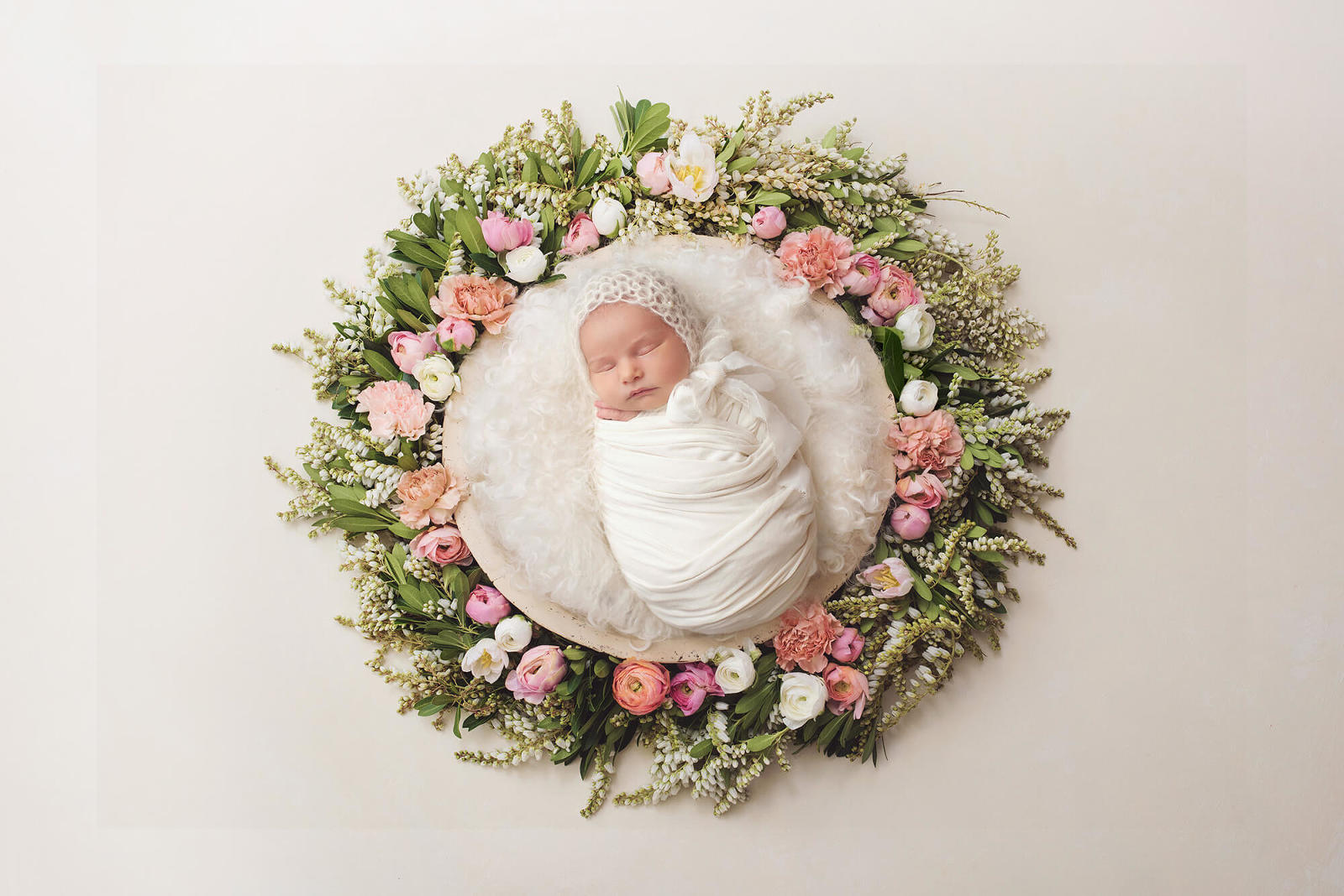 Baby girl during her newborn session laying in a plush nest surrounded by flowers and greenery during her session with Belle Vie Photography in Tucson
