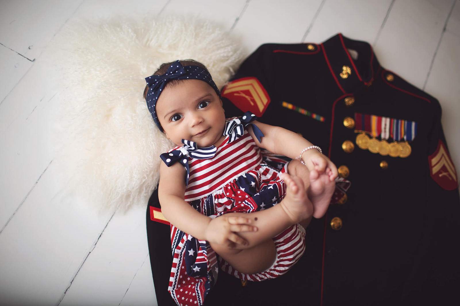 Baby Evelyn during her 3-month milestone session with her daddy's Marine Corps uniform