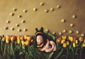 Newborn baby dressed as a bee laying in a nest of yellow tulips by Wiesbaden newborn photographer