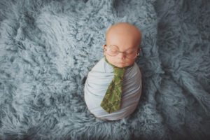 newborn boy wearing a tie and glasses by clay Kaserne newborn photographer