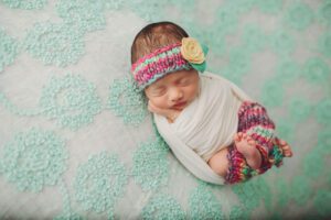Newborn baby girl wearing leg warmers and a headband during her newborn session with Belle Vie Photography of Wiesbaden