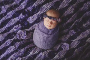 newborn girl on a purple blanket her mom handmade by Ramstein newborn photographer