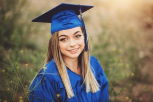 A Catalina Foothills High School senior proudly wears her cap and gown surrounded by sunlight and desert wildflowers