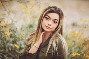 A senior at Catalina Foothills High School poses gracefully amongst the yellow desert flowers of spring during her senior session with Belle Vie Photography in Tucson