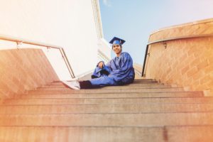 A Catalina Foothills High School sits on the steps of his Tucson high school in his cap and gown during his senior session with Belle Vie Photography