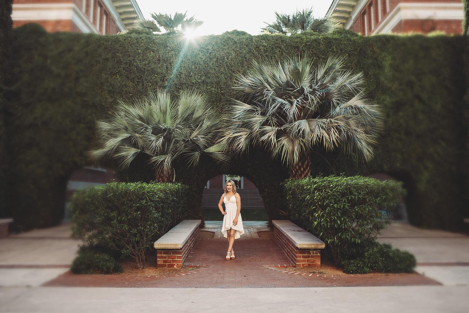 University of Arizona senior, Shelby, poses in front of a foliage covered campus building during her senior portrait session at U of A