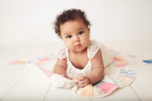 Baby girl lying on a colorful quilt during her 6-month studio milestone session