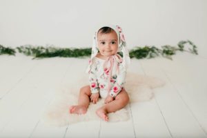 Baby girl in a floral romper with matching bunny ears during her 6-month studio milestone session