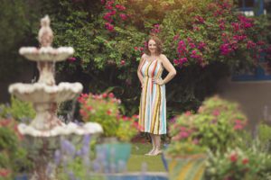 Woman stands amongst bougainvillea and potted flowers in a courtyard at Hacienda Del Sol during her glamour session.