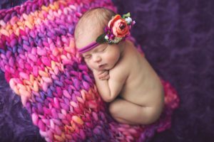 Newborn baby girl in bright pink and purple