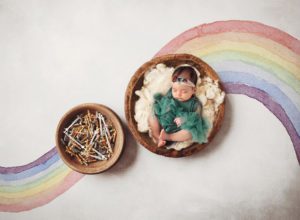 Newborn baby girl with a rainbow and IVF needles to represent her family's IVF journey
