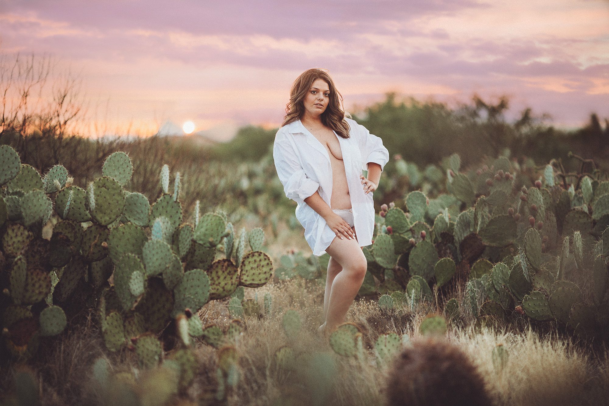 A young woman in a white shirt during her desert sunset boudoir session