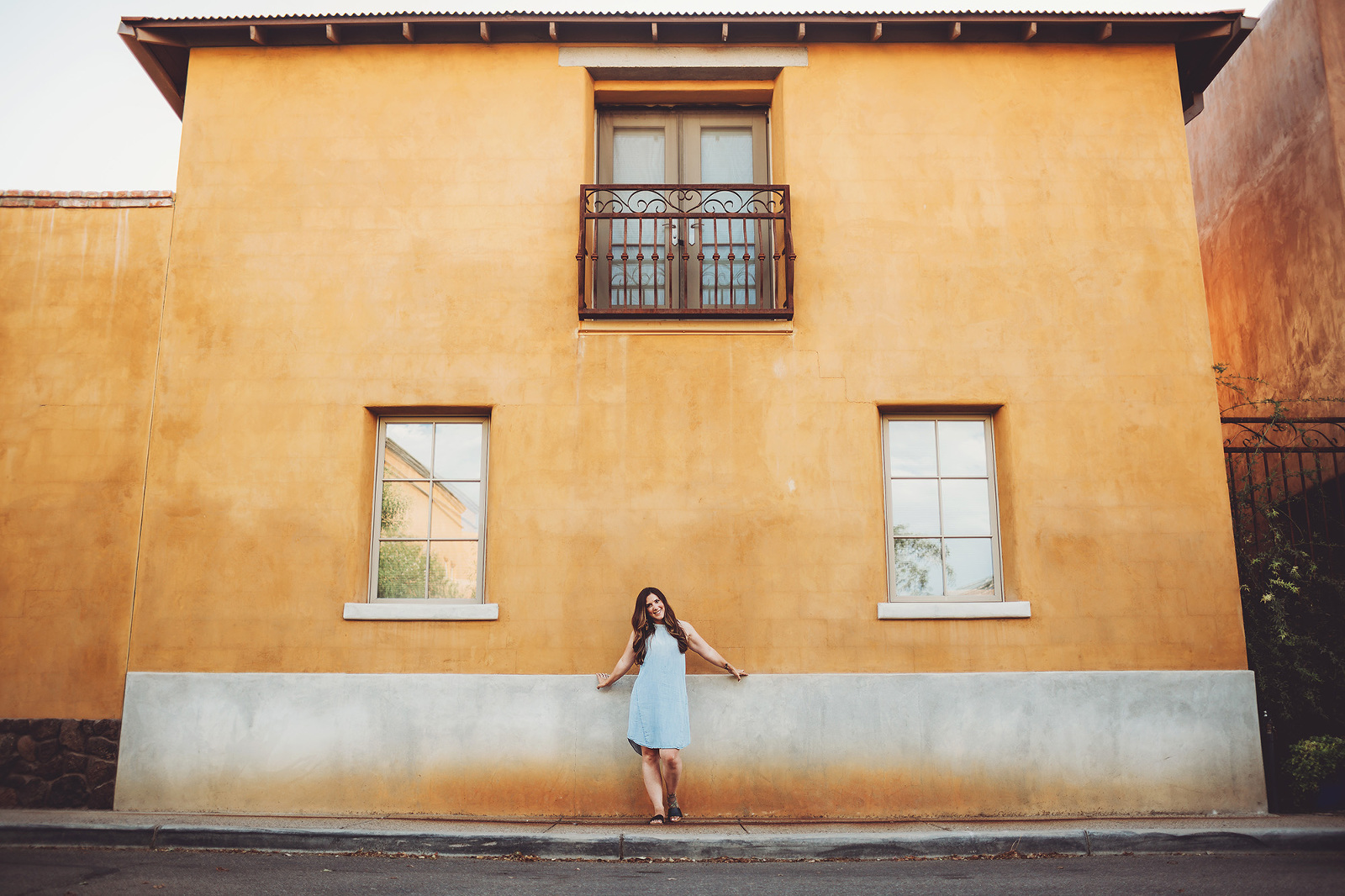 A woman standing next to a traditional-style Tucson home during her portrait session in downtown Tucson