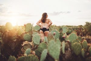 A young woman poses in black lace underwear during her sunset, desert boudoir session