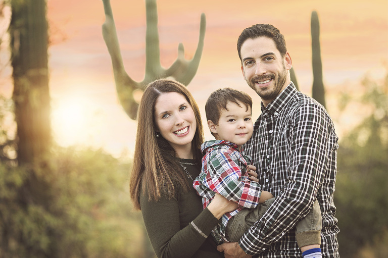 A mom and dad with their son amongst the desert saguaros in Tucson during their holiday family photo session