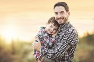 Father and son cuddles at sunset during their family holiday photo session in Tucson