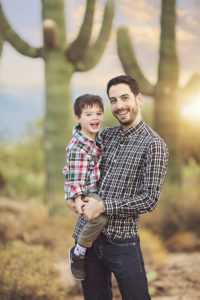 Father and son laughter with a saguaro and sunset backdrop in Tucson during their family holiday photo session
