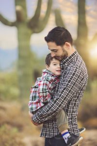 Father and son cuddles with a saguaro and sunset backdrop in Tucson during their family holiday photo session