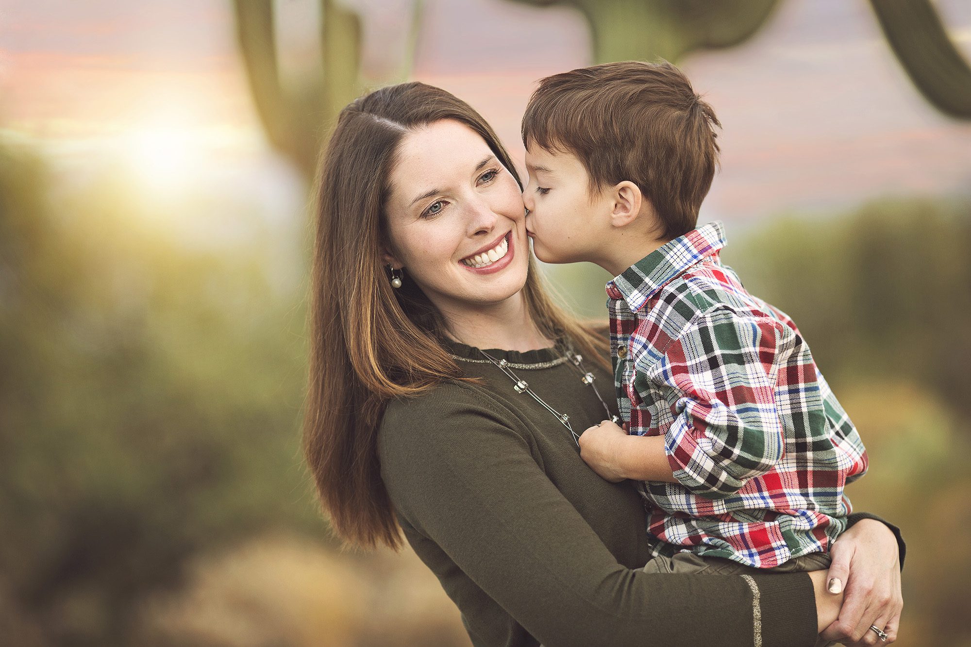 Mother and son love during a family holiday photos session in the Tucson desert with a saguaro and sunset backdrop