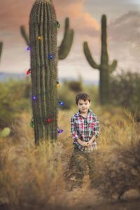 Little boy and his first desert Christmas with a saguaro dressed in Christmas lights during a holiday family photo session in Tucson