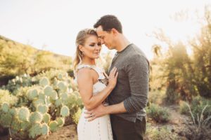 A husband and wife share a warm moment and loving bond in the warm sunlight of Gates Pass during their family session with Belle Vie Photography in Tucson
