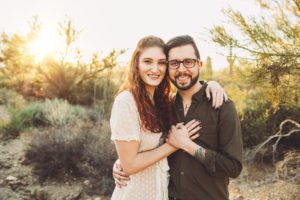 A young couple visiting Tucson snuggle under the desert sun during their family photo session at Gates Pass