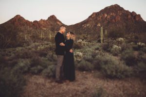 A husband and wife hold one another with Gate's Pass behind them at sunset during their family photo session with Belle Vie Photography in Tucson