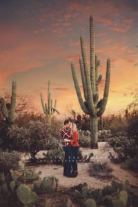 A couple kiss under an Arizona sunset by a giant saguaro during their sunset couple's session in Tucson