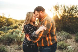 A couple shares an intimate moment in the desert during their sunset family session at Gates Pass in Tucson