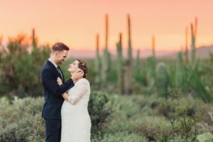 A couple lovingly gazes at one another surrounded by saguaros and a breathtaking sunset during their elopement at Gates Pass in Tucson