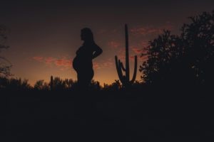 Alicia stands against the colorful Tucson sunset during her maternity session