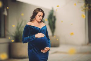 Maternity session in downtown Tucson during spring with a blue velvet dress and falling yellow palo verde tree flowers