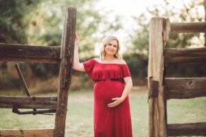 Beautiful Jane leans against a wood fence during her sunset maternity session