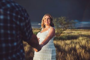 Janes gazes at her husband while storms rage around them during their sunset maternity session in Sonoita