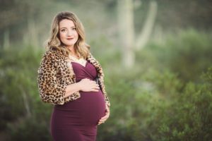 A gorgeous mom to be cradles her baby bump in a beautiful plum gown during her maternity session in Tucson