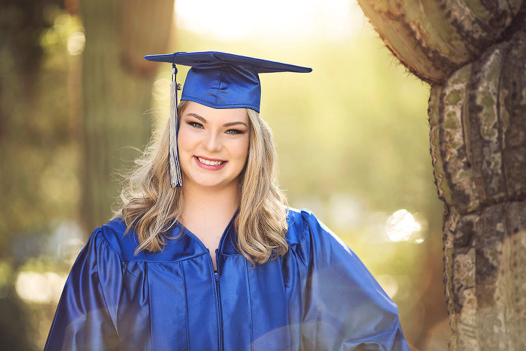 Olivia stands amongst the saguaros near Old Main at the University of Arizona campus in her cap and gown during her senior portrait session