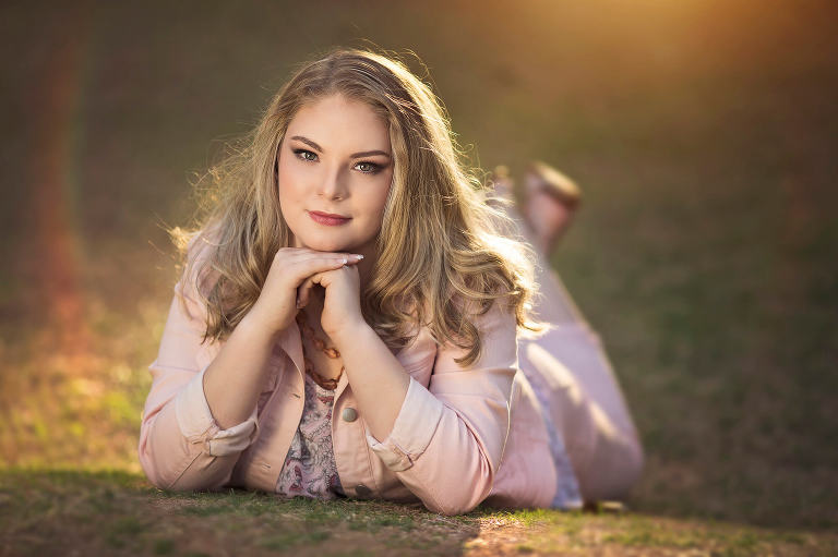 High school senior Olivia replicates a childhood photo by laying on her belly and resting her chin on her hands during her senior portrait session at the University of Arizona