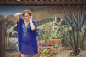 Mandy wearing an electric blue swim cover-up in front of a desert mural with adorning color plant pots