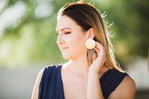 A woman showcasing a pair of earrings made by Luna + Saya during a business photoshoot