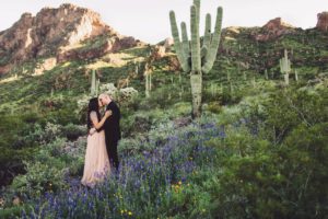 A couple kisses amongst the desert wildflowers of Picacho Peak during their engagement session with Belle Vie Photography