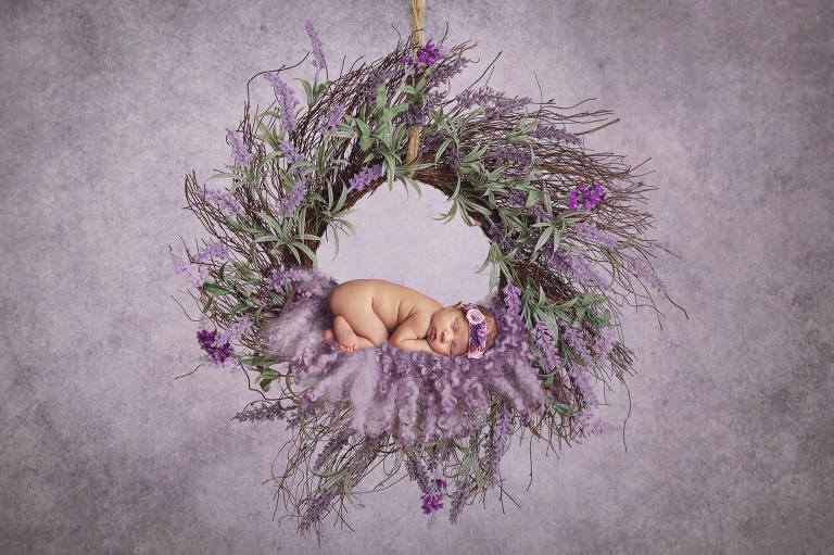 Newborn Valentina cuddled in a purple floral wreath during her newborn session with Tucson newborn photographer Belle Vie Photography