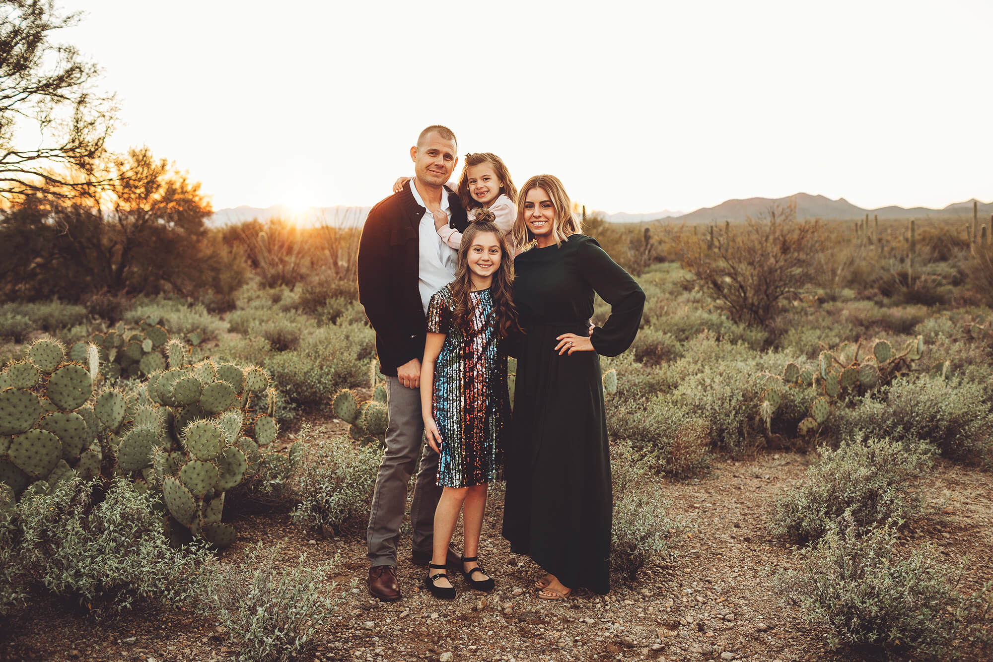 The Gunter family looks amazing as they stand amongst the beautiful Sonoran desert, the setting sun at their backs during their family photoshoot near Tucson with Belle Vie Photography
