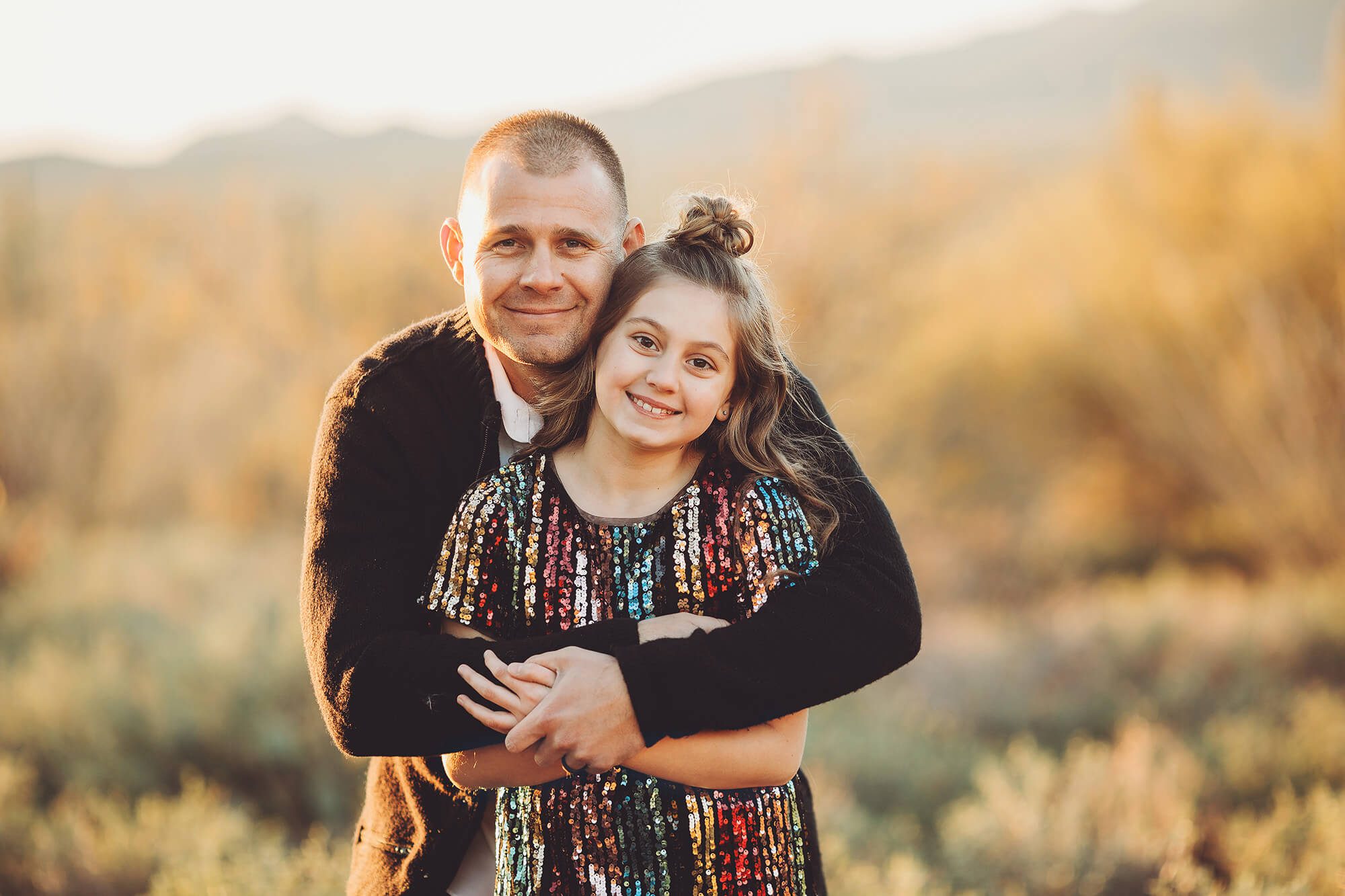 A dad holds hugs his daughter during the Gunter's family photo session just before sunset at Gates Pass in Tucson