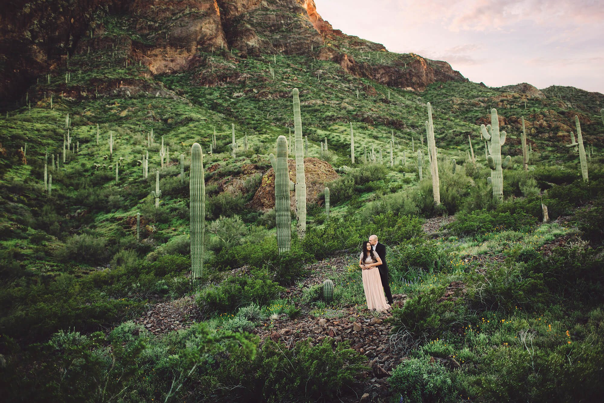 The Paxman's hold one another at the base of Picacho Peak surrounded by spring growth