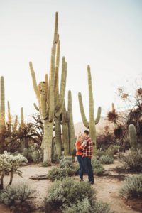 The Freeman's hold one another as the giant saguaros behind them make them look tiny