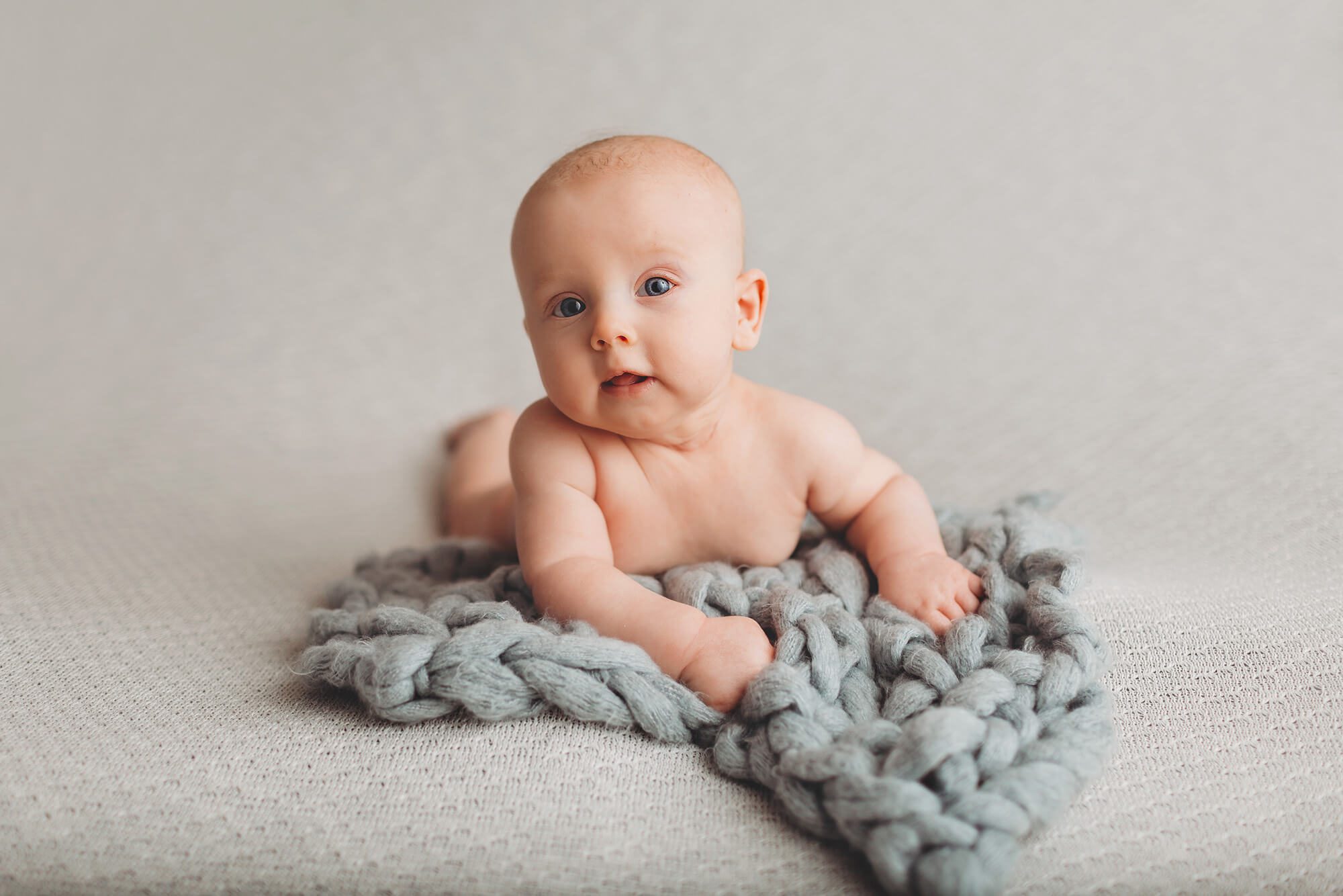 Three-Month milestone session with baby boy on a pale blue bump blanket