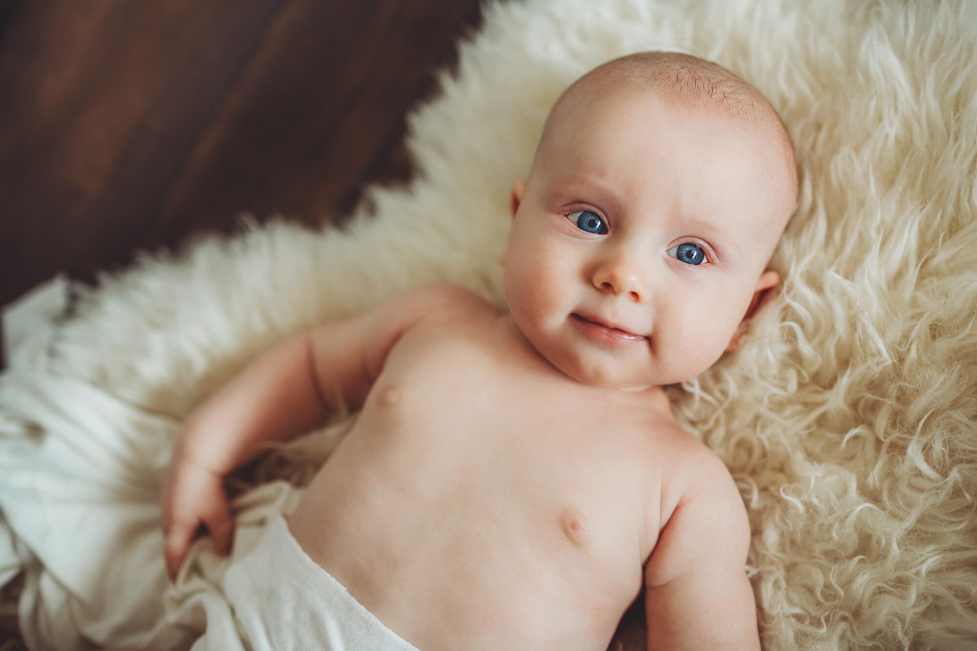 Three-month old session of a baby boy with brilliant blue eyes on a fur rug in Tucson with Belle Vie Photography