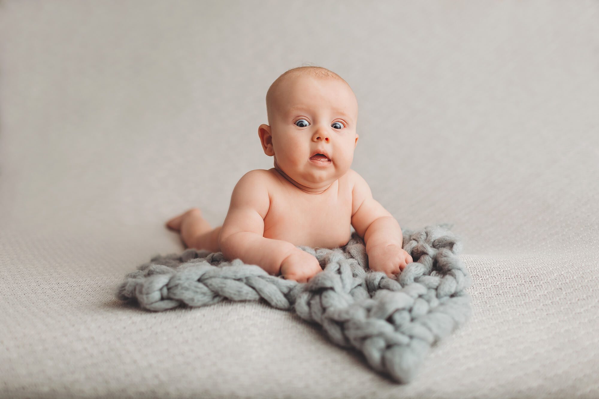 A very surprised look by a baby boy during his three-month milestone session with Belle Vie Photography