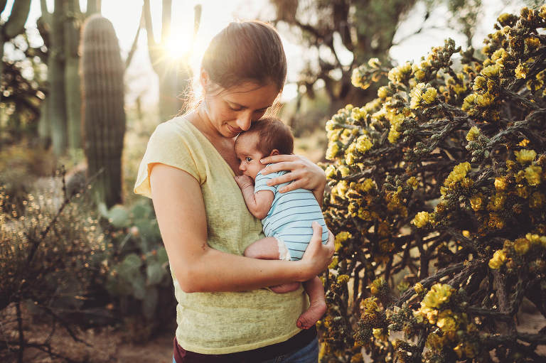 Mom holds her baby close amidst the sunlight and yellow blossoms of spring in the desert.